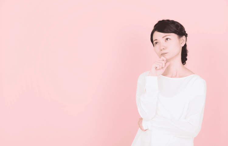 ピンクの背景で転職について考える女性